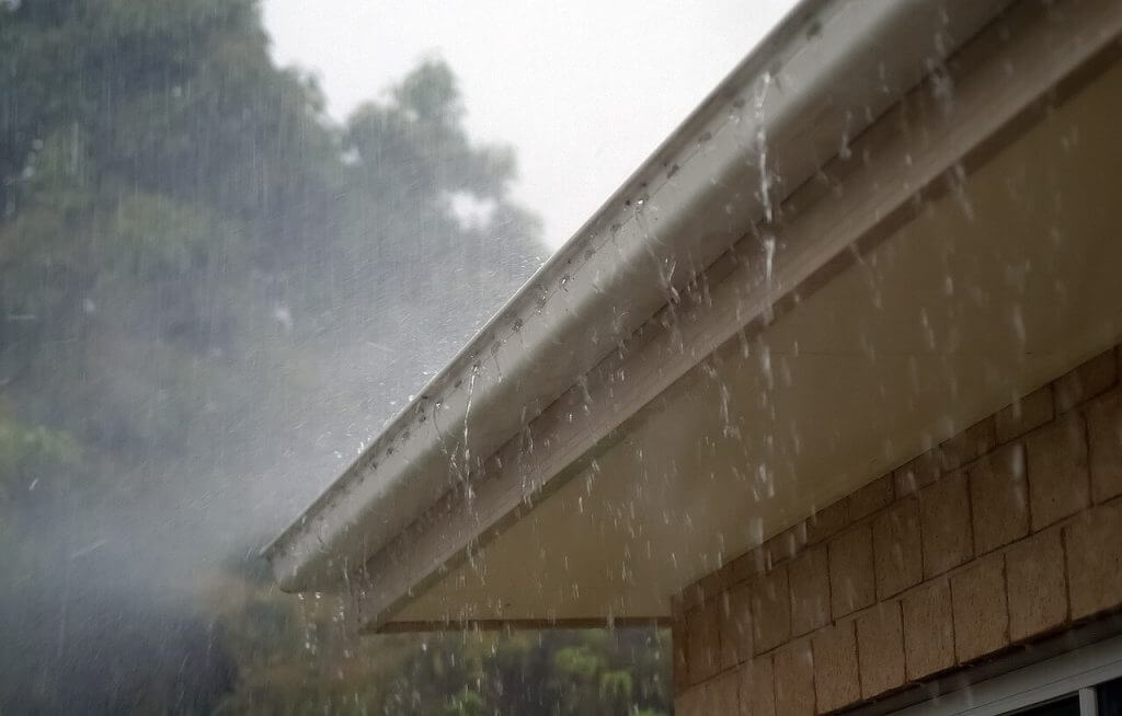rainwater leaking over the side of a roof