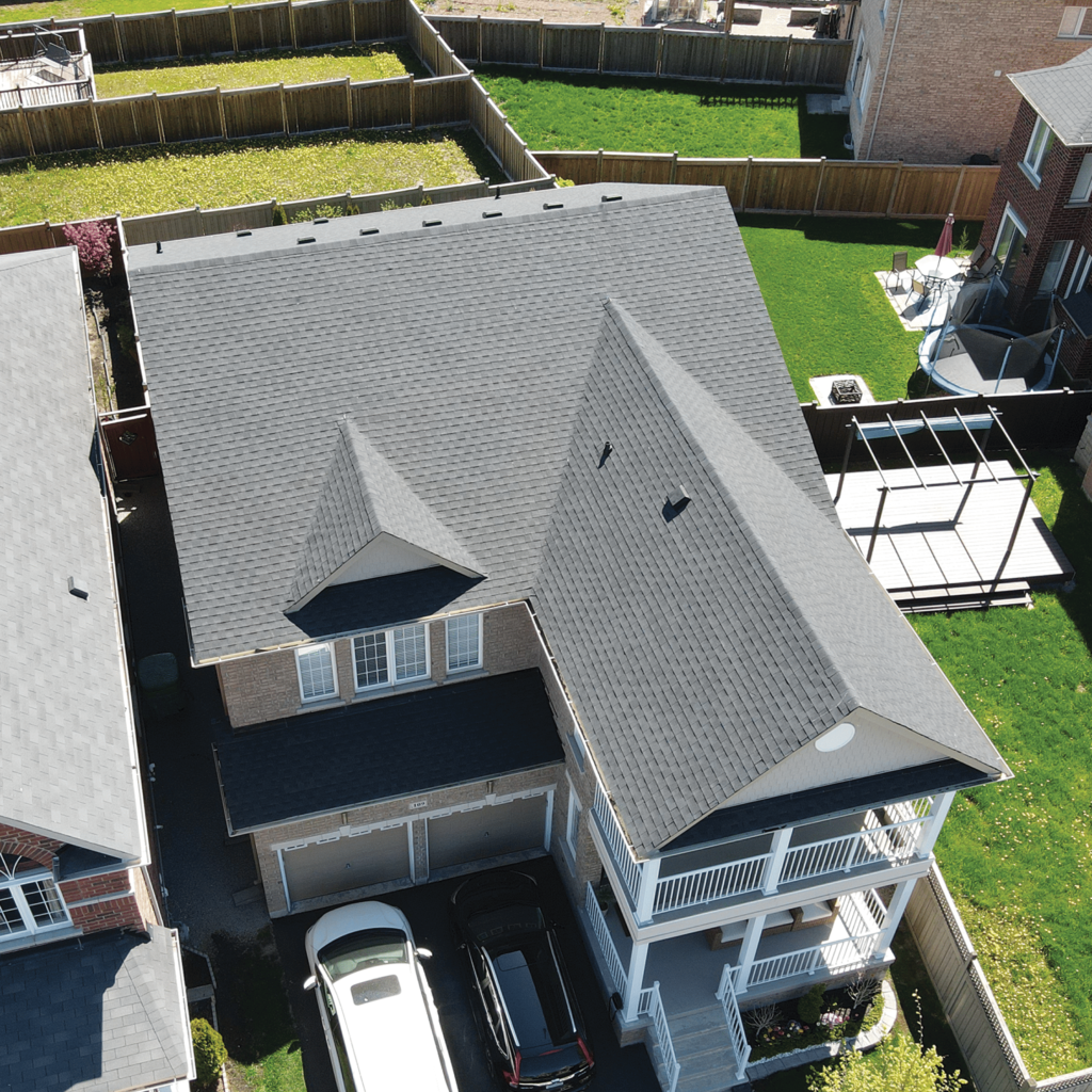 Aerial view of a two-story brick home with a newly installed asphalt shingle roof, a completed roofing project by The Roofers in Markham