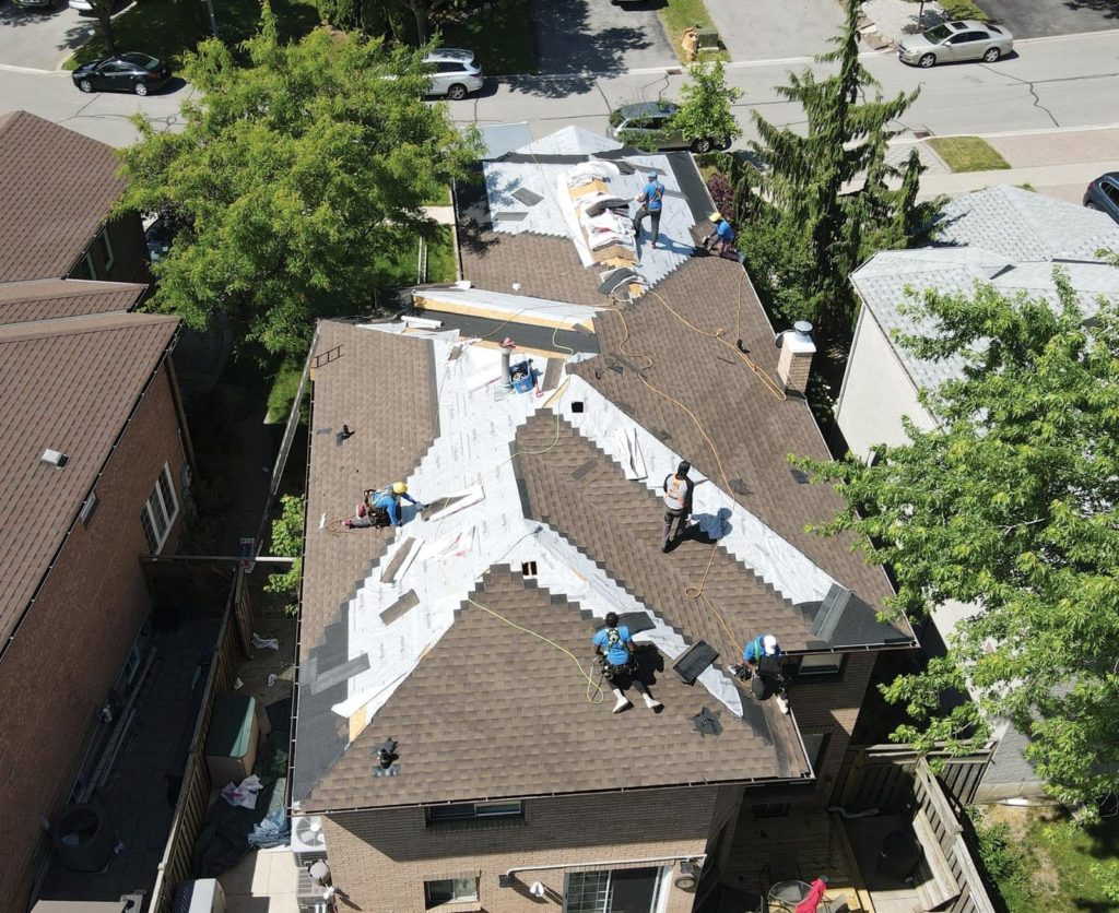 Aerial view of roofers installing asphalt shingles on a brick home, completing a roofing project by The Roofers in Markham