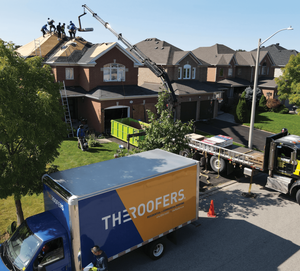 Roofers in action using a crane to install shingles to complete a roofing project by The Roofers in Aurora